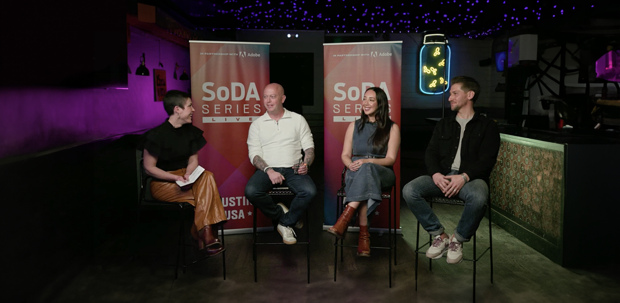 Four people sitting at a panel discussion with banners that read "SoDA Series"