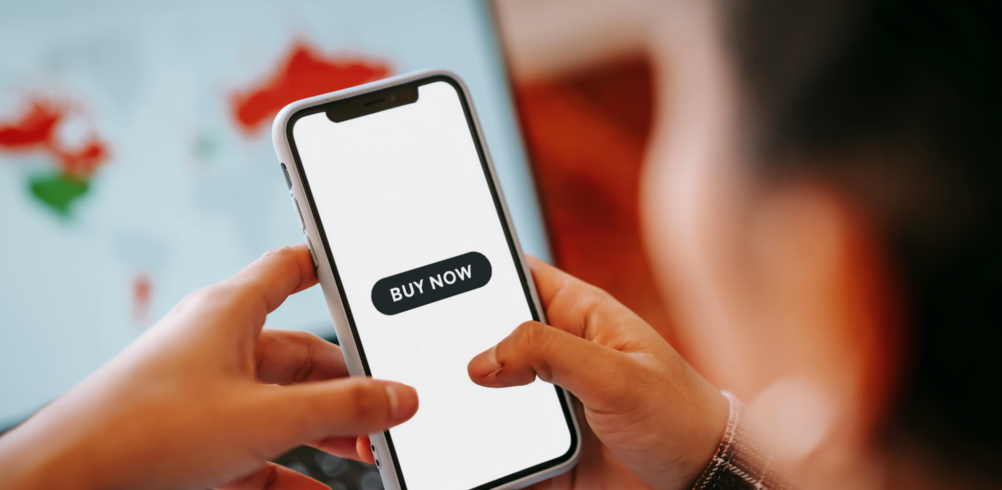 Person looking at their phone at a button saying, "buy now."