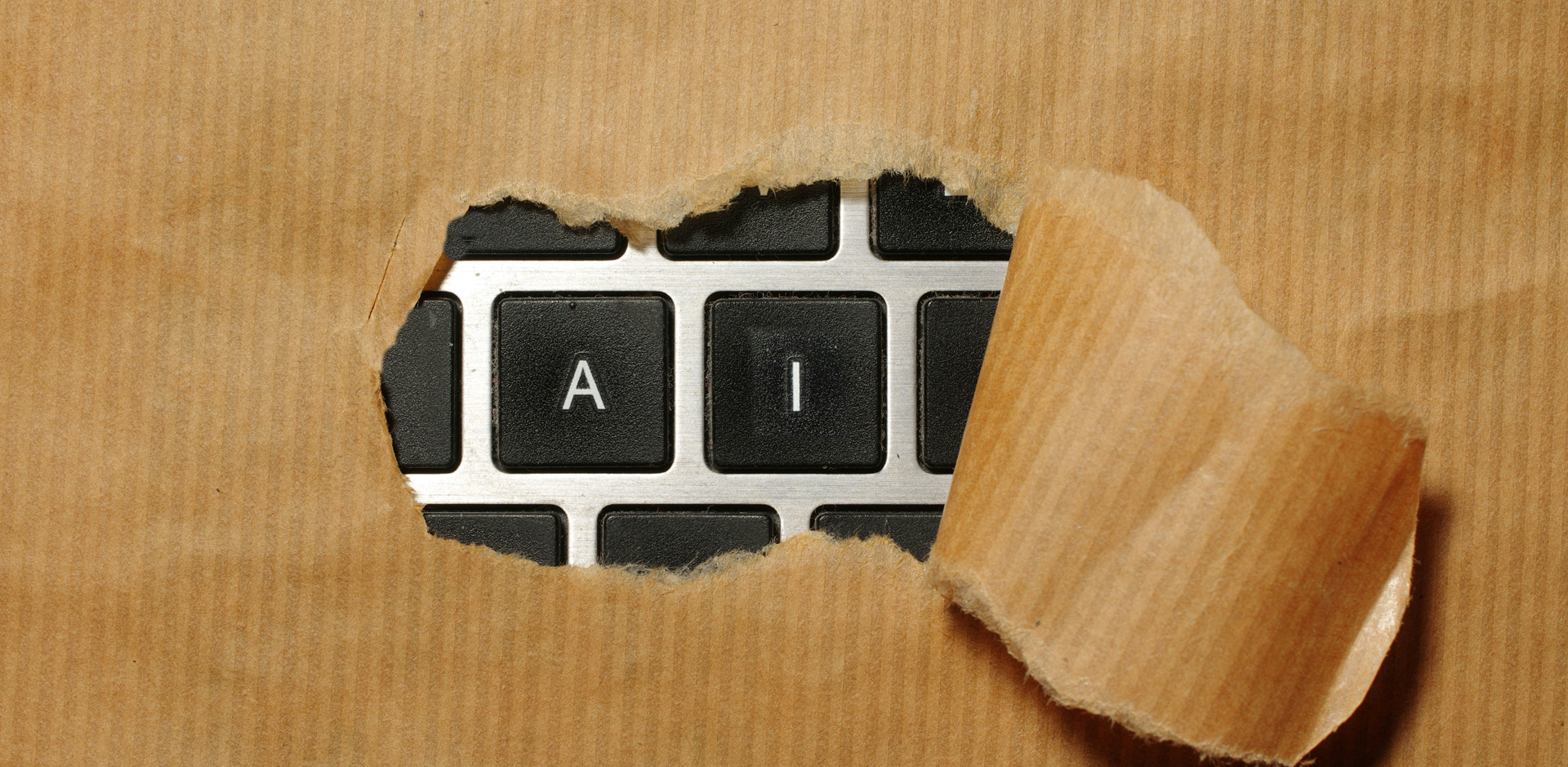 A keyboard being showing behind ripped paper