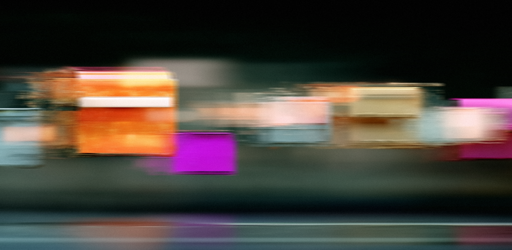 An abstract photograph of colorful rectangular shapes streaked horizontally with motion blur against a dark background.