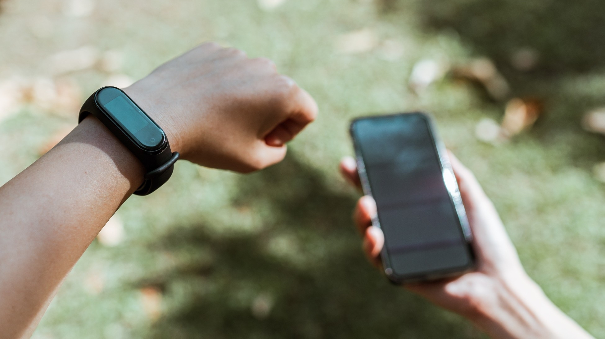 A person wearing a device on their wrist and holding a phone
