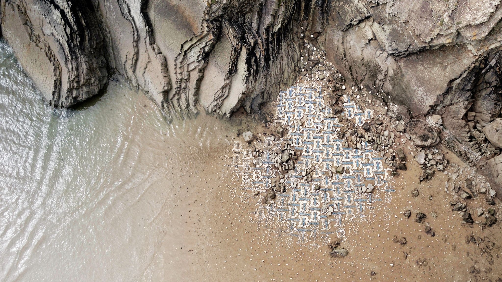 A shoreline of rock sculptures in the shape of the Burberry TB Monogram