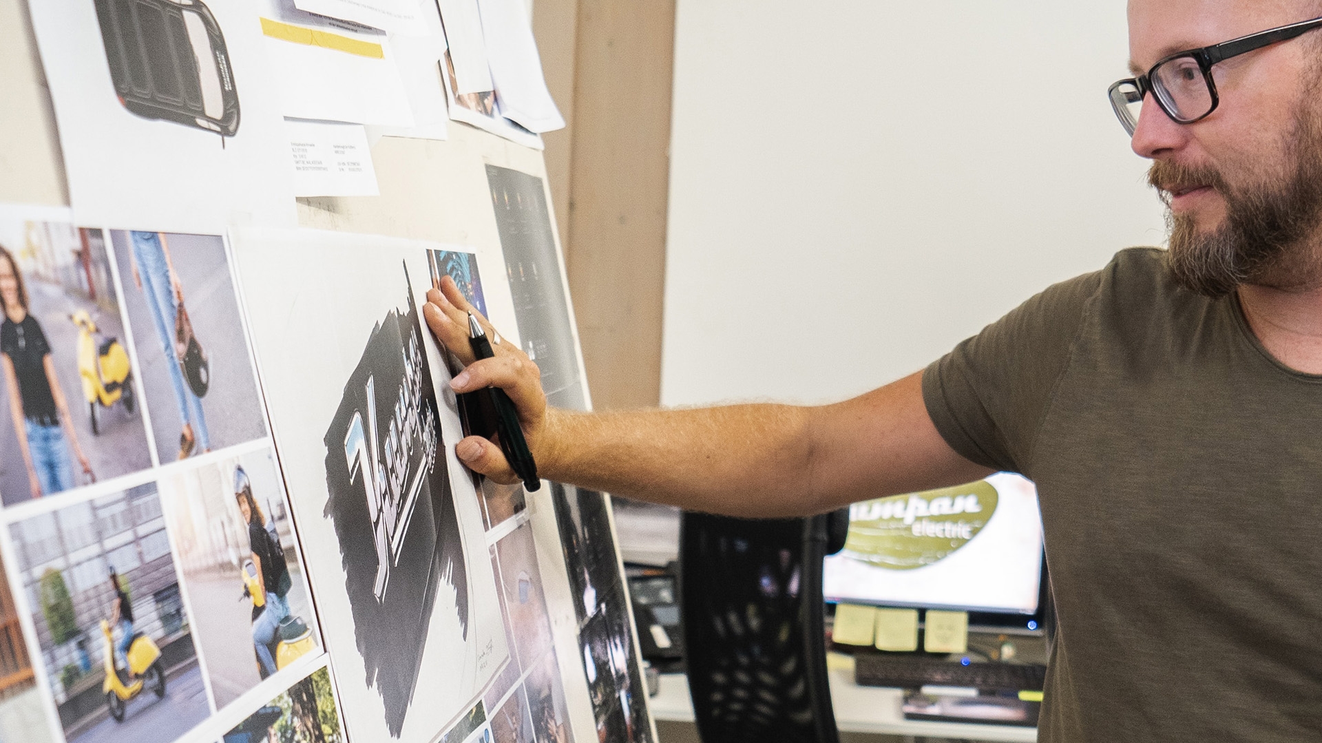 A person looking over pictures on a wall with a pen writing notes