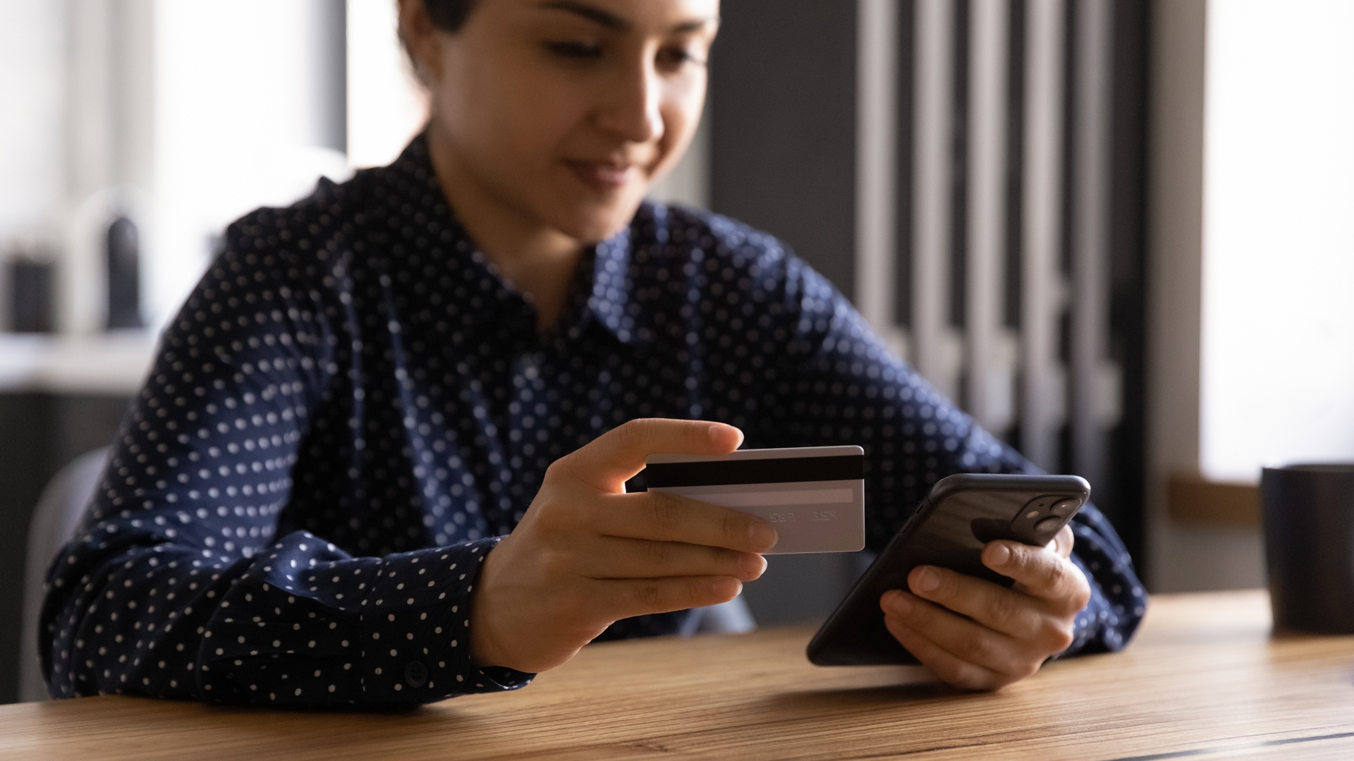 A woman holding a credit card and phone