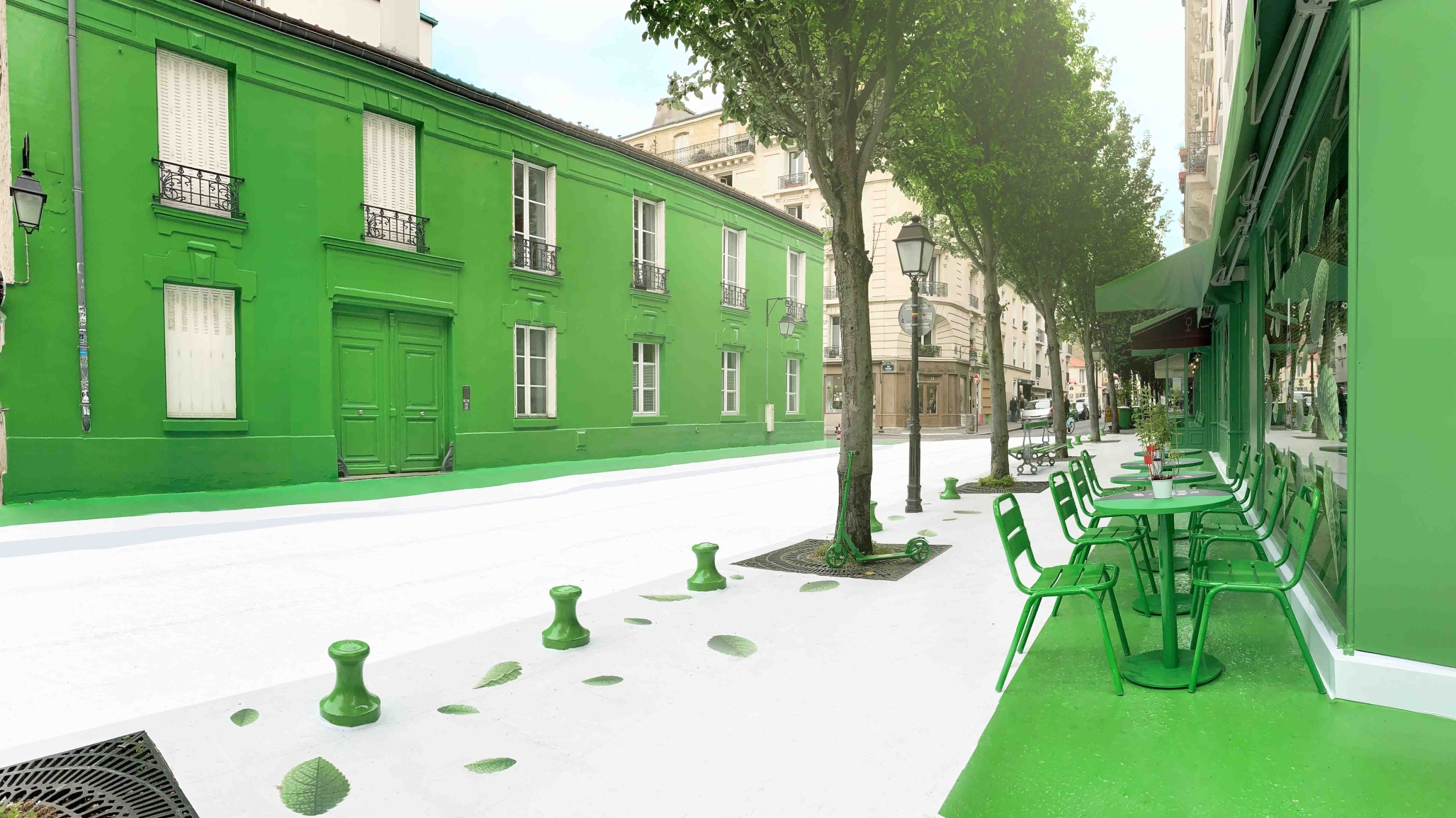 A green painted street with green tables, chairs, and street signs