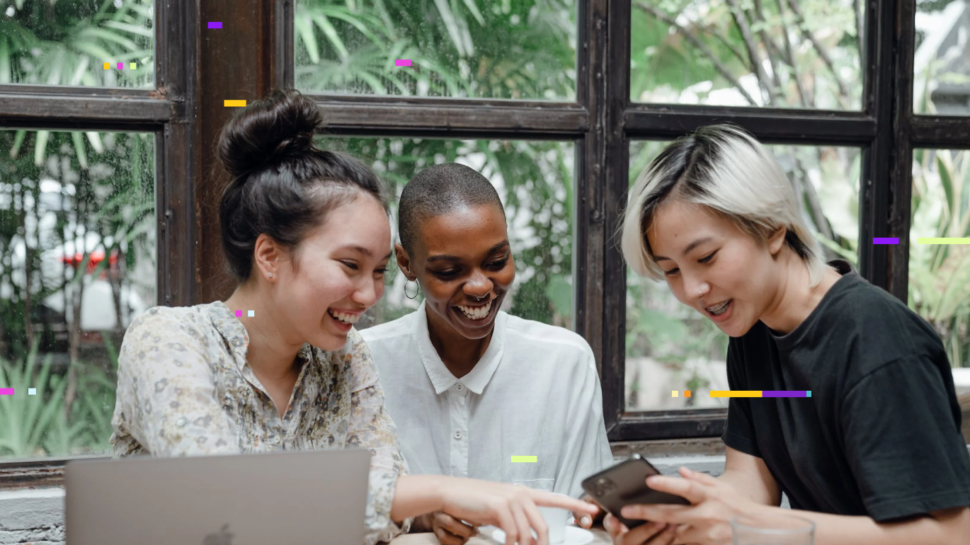 Three employees looking at an iPhone together laughing