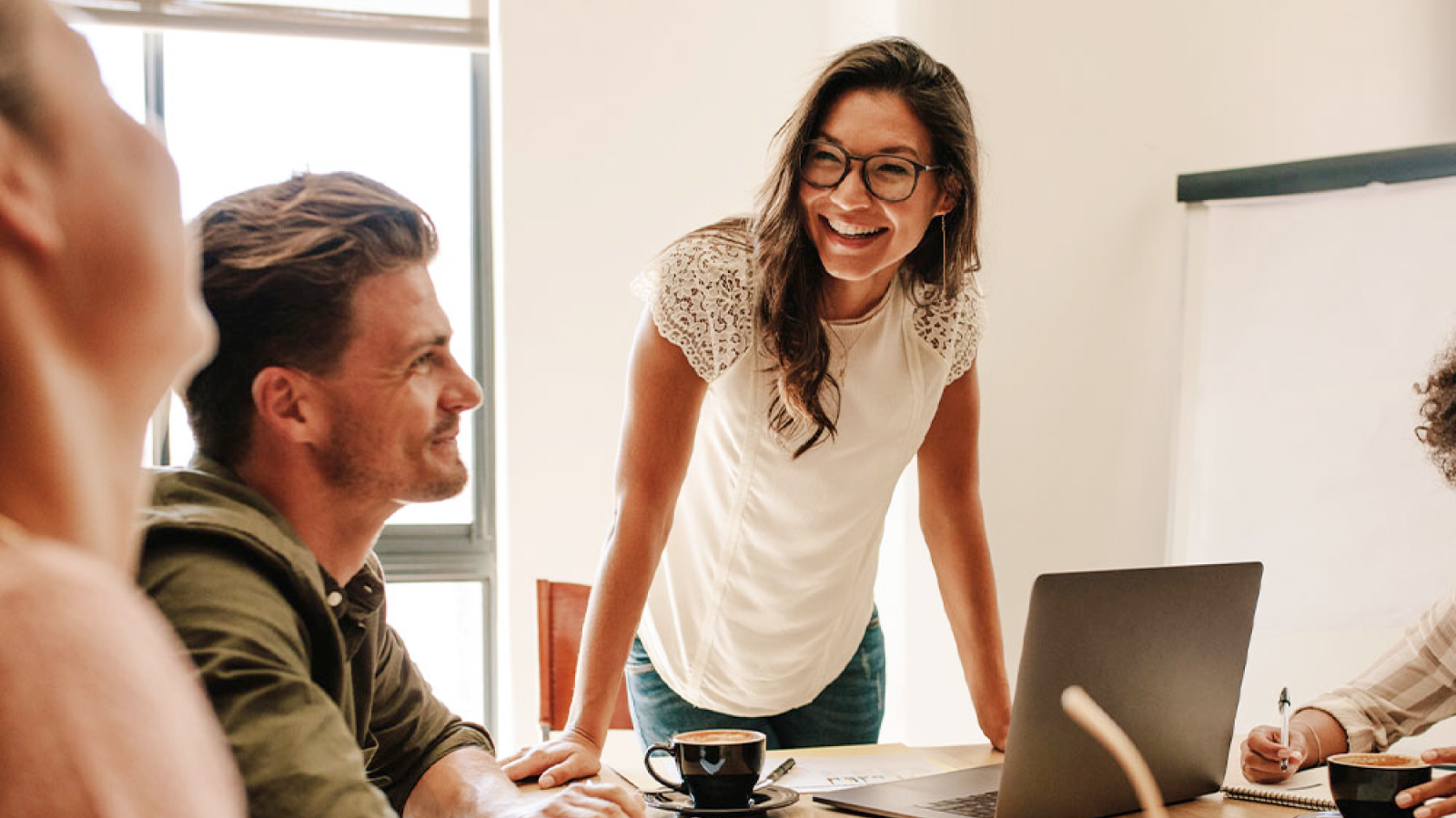 Coworkers talking and laughing over laptops