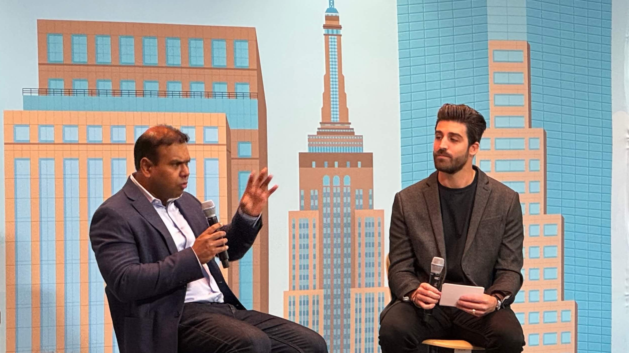 Kosta Demopoulos and Randip Mitra sit together on the Brand Innovator stage, engaged in conversaion.