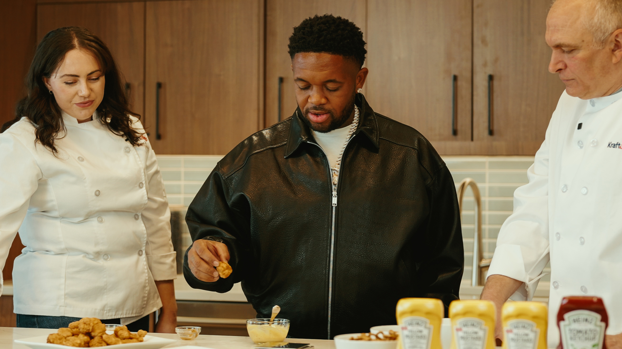 DJ Mustard stands beside two chefs for a taste test.