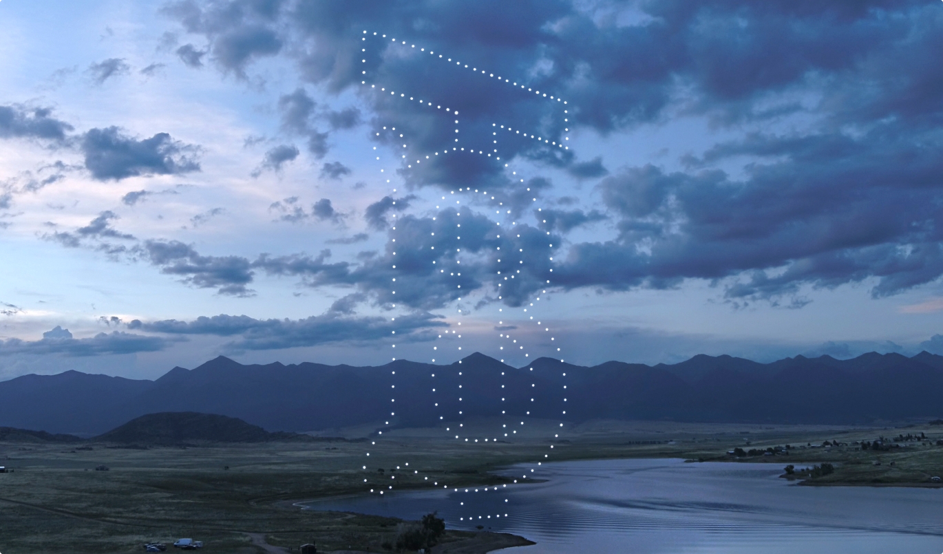 TB monogram made from lights in the night in front of mountains