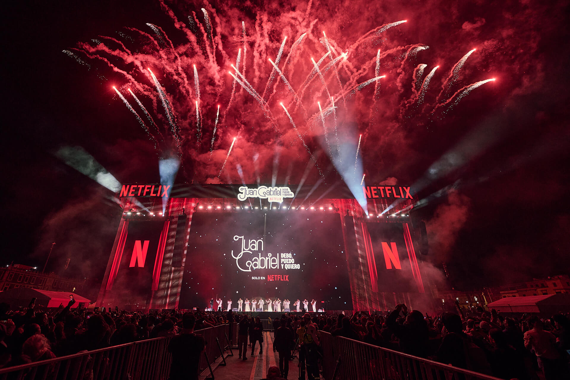 The massive stage for the Juan Gabriel Netflix screening in the Zócalo filled with fans. There are fireworks exploding in the background.