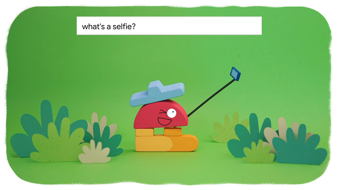 Animation of a shape based character holding a selfie stick. With at the top a Google search bar with the question: what's a selfie?