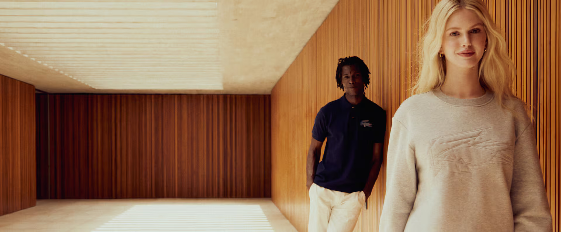 Two Lacoste models leaning on a wall