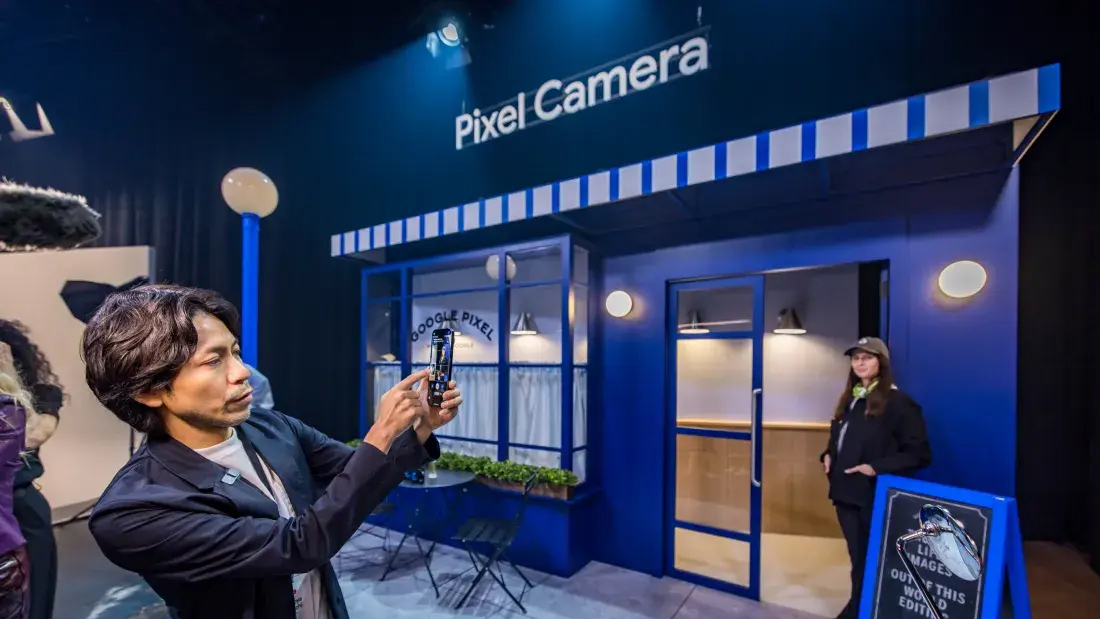 man holding phone in front of a purple building that reads "Pixel Camera"