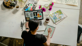 A person working at a desk with design applications open on their computer