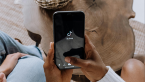 A cellphone showing the tiktok app on it's interface being held by someone