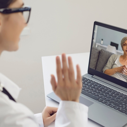 A doctor waiving to a patient via a laptop telehealth appointment