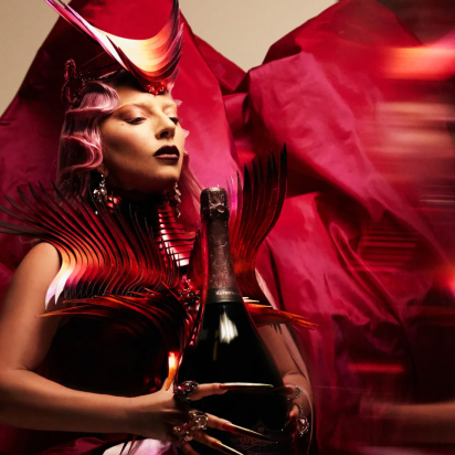 Lady Gaga holding a giant champagne bottle in a large red dress