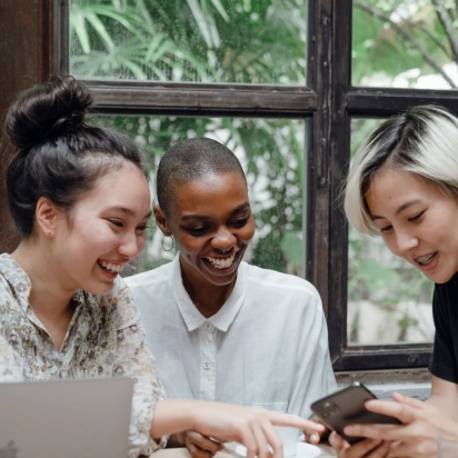 Three employees looking at an iPhone together laughing