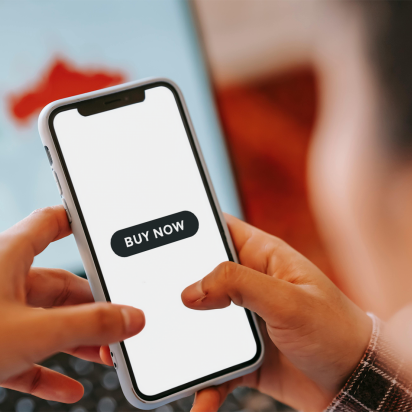 Person looking at their phone at a button saying, "buy now."