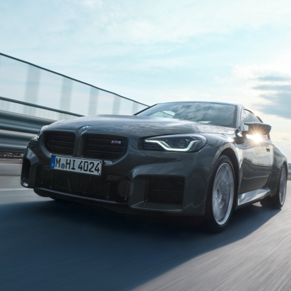 bmw driving on a street with a city in the background