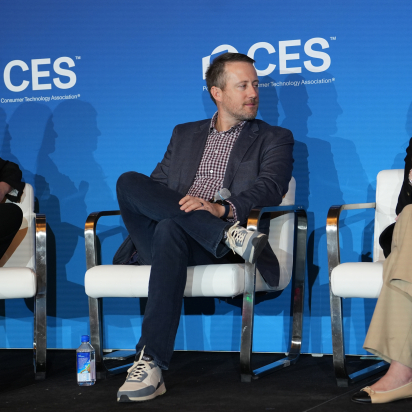 three people sitting on a stage at CES