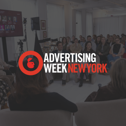 A panel discussion in progress at an event, with the "Advertising Week New York" logo overlaid in the center. In the background, a group of panelists sits in a semi-circle of chairs facing an audience, with a large screen displaying speaker headshots on the wall.