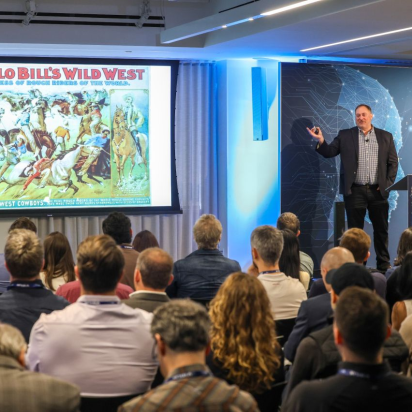 A presenter from the IAB Tech Lab showing a vintage advertisement to a room full of marketing industry leaders.