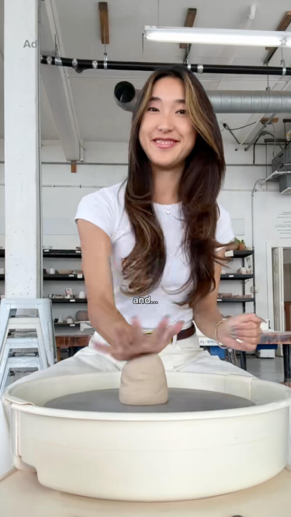 A female dove partner sitting at a clay spinning wheel with beautiful hair