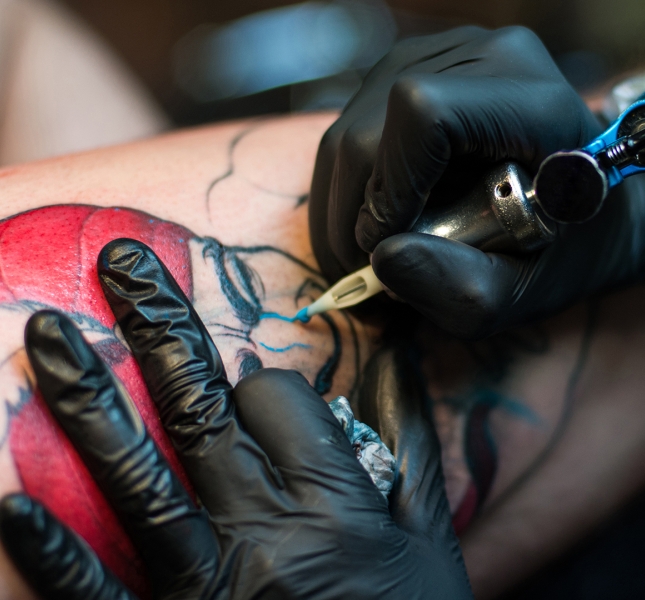 A tattoo artist giving a person a tattoo on their arm