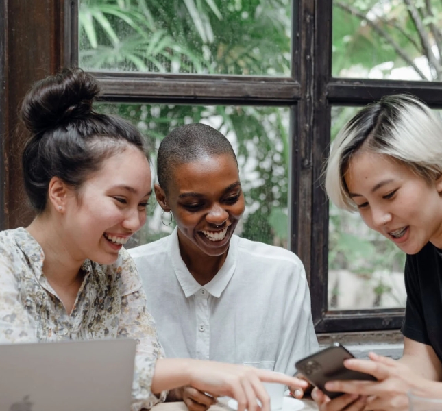 Three employees looking at an iPhone together laughing