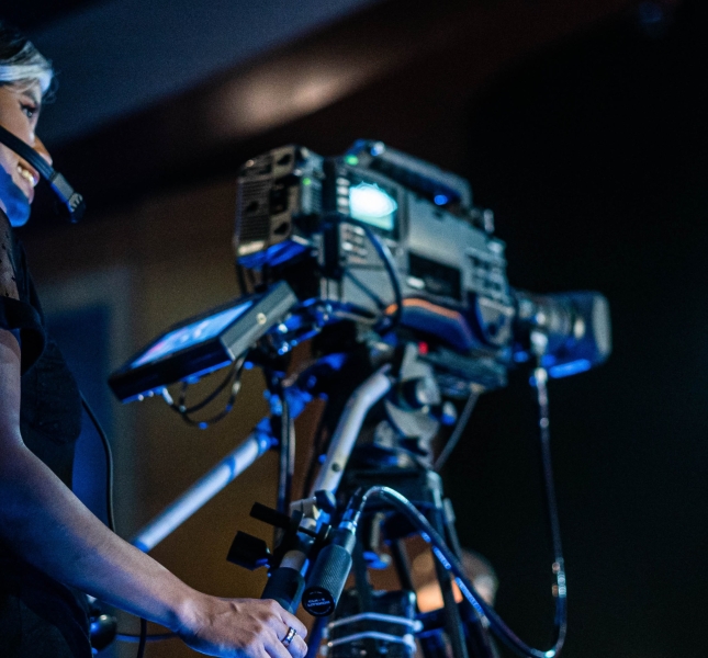 Image that features woman behind a filming camera