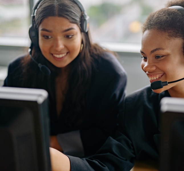 Two business women discussing a call over their desktop computers