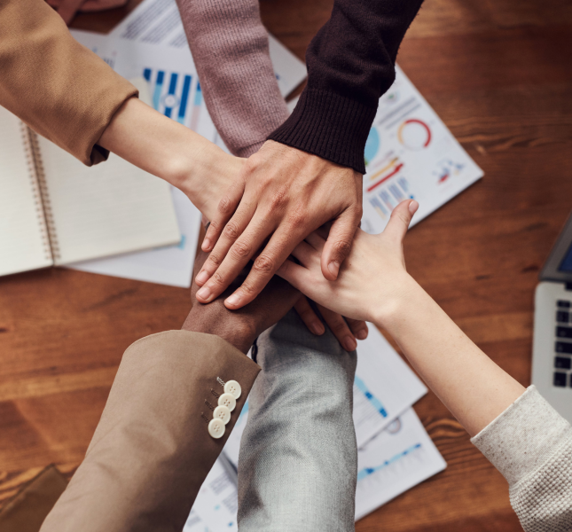Diversas mãos uma sob a outra em cima de uma mesa