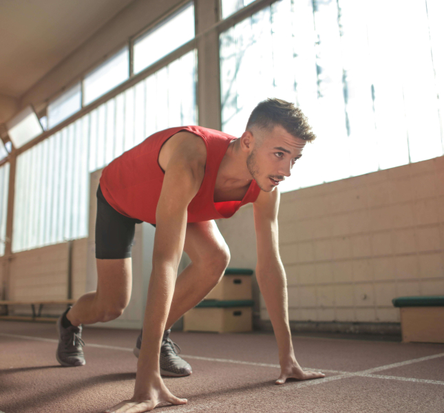 homem em posição de largada para corrida vestindo roupas de atletismo vermelhas