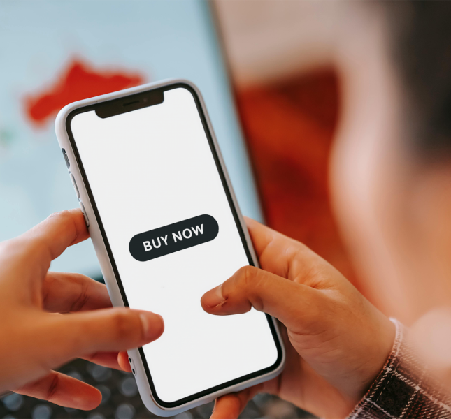Person looking at their phone at a button saying, "buy now."
