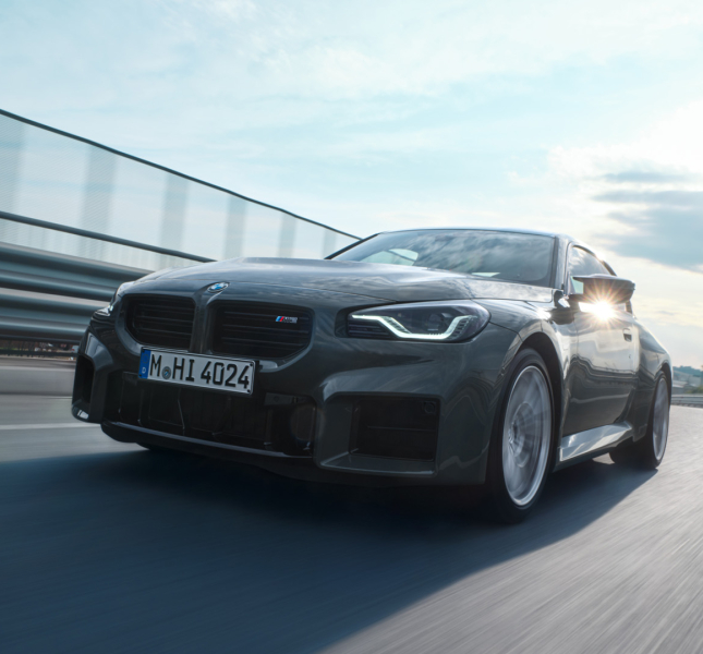 bmw driving on a street with a city in the background