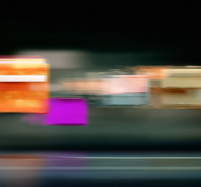 An abstract photograph of colorful rectangular shapes streaked horizontally with motion blur against a dark background.