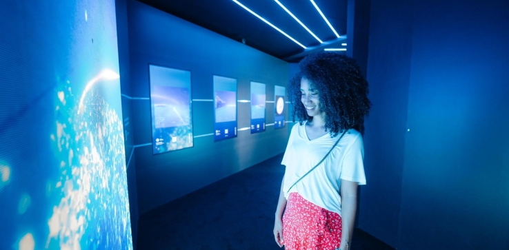 A person views LED screens in a dark exhibit hallway