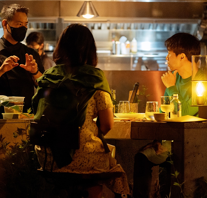 A couple sitting at a table at night with yellow light keeping them lit