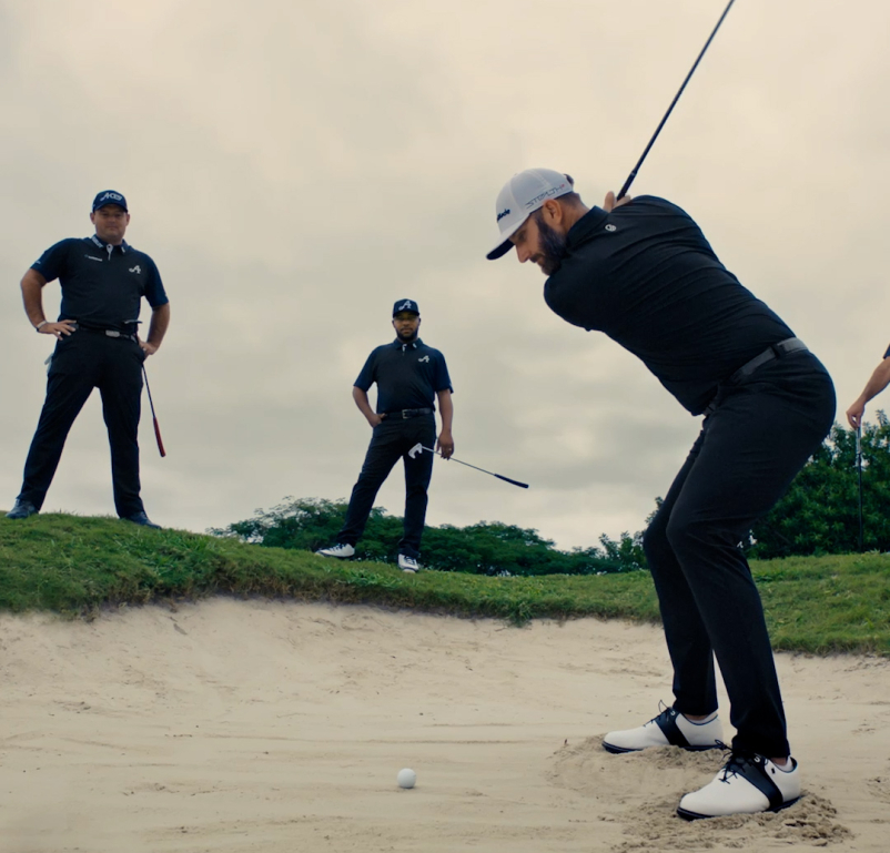 Dustin Johnson swinging in the bunker with team mates around him