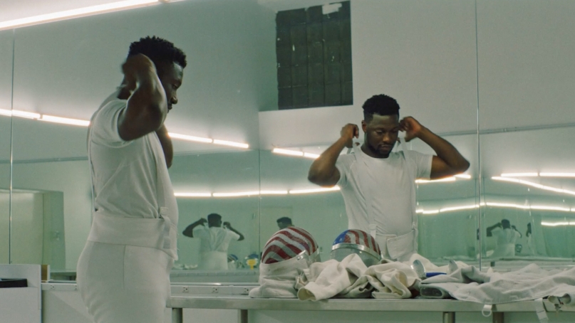Athlete putting on fencing equipment against a mirror reflection
