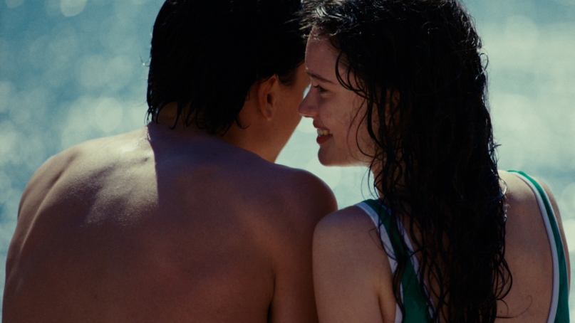 Two people seen from the back in bathing clothes almost kissing each other