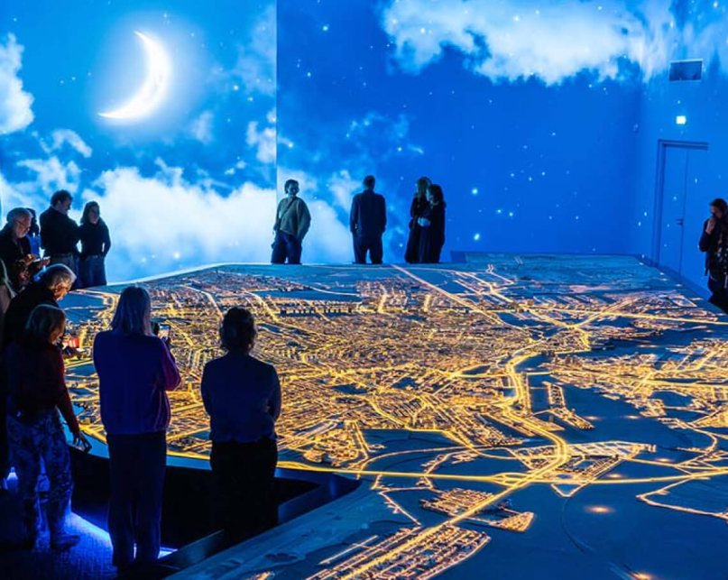Amsterdam Museum guests viewing an immersive illuminated display of their city at night at a new exhibit.
