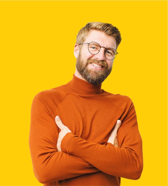 A person smiling with their arms folded on a yellow background