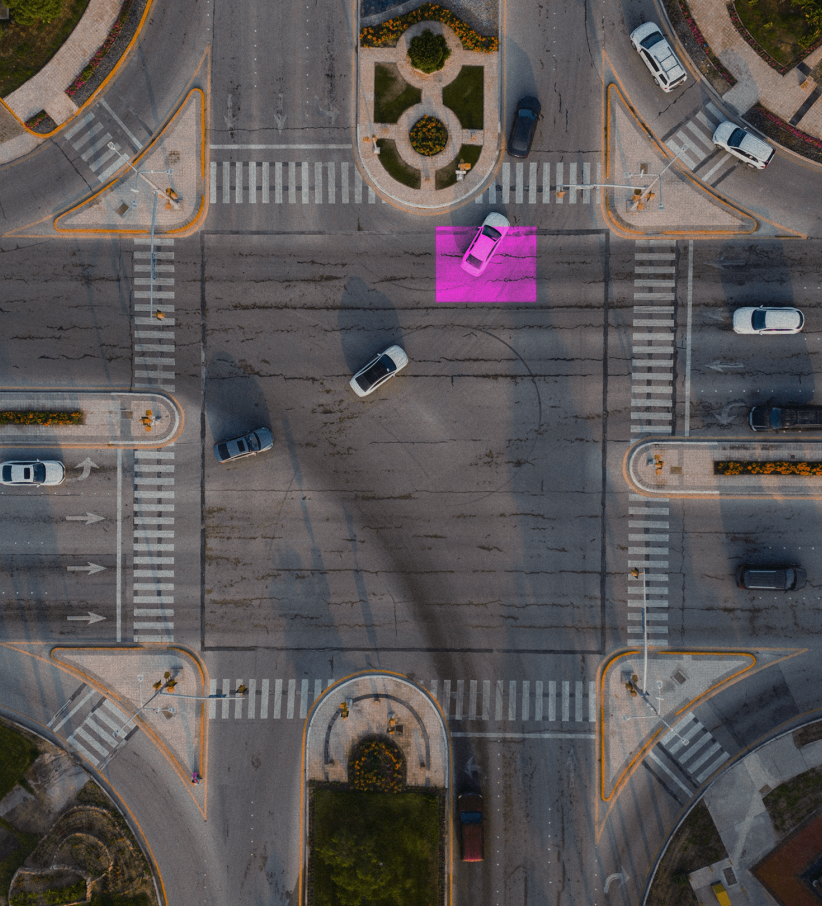 A birdeye view of a crossroad in a city environment showing traffic cars turning in all directions