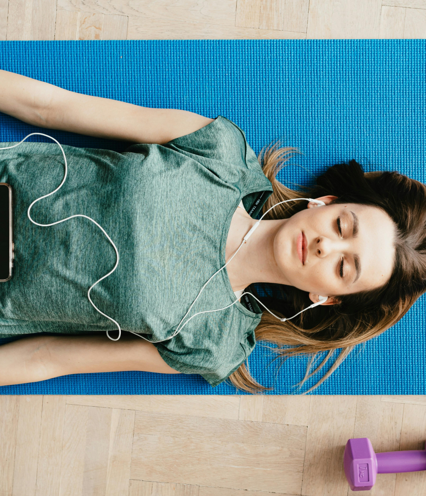 A woman laying on a yoga mat with headphones in