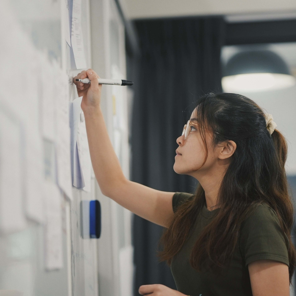 A woman working at a whiteboard writing