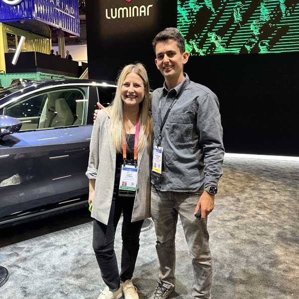 Two people on floor at CES in front of a car