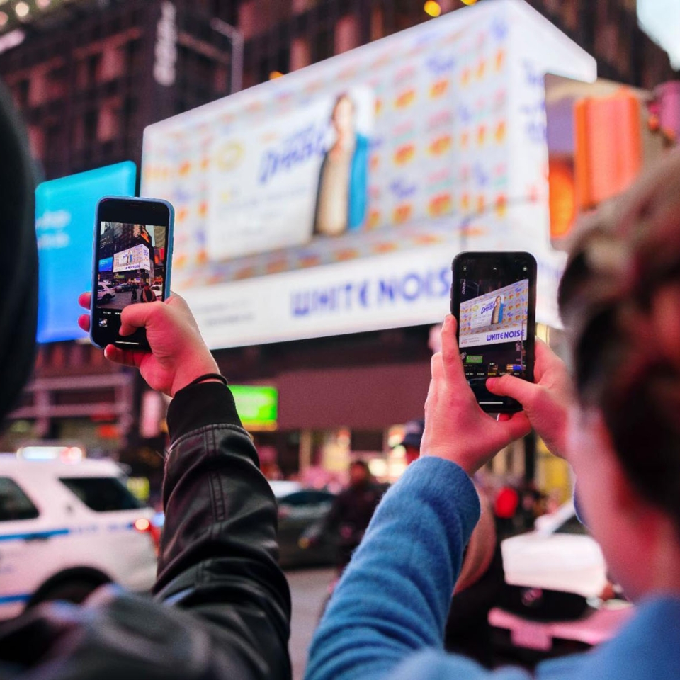 People taking photos on their phone of a billboard